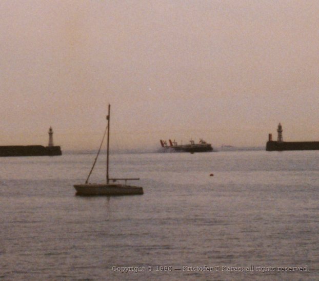 Sailboat and ferry share the waters of Dover Harbor, England