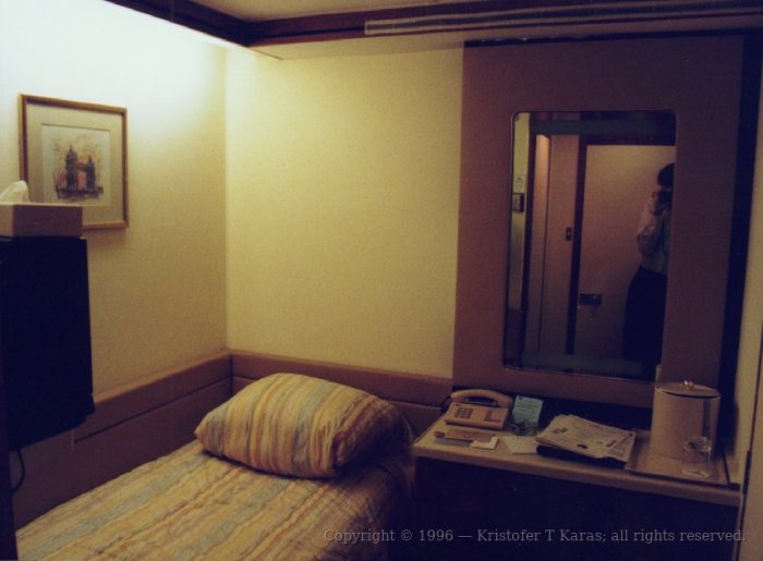 Bed and table in author's stateroom aboard QE2, author in mirror