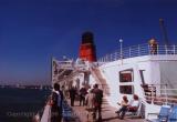 White deck, red funnel, and deep blue sky behind QE2